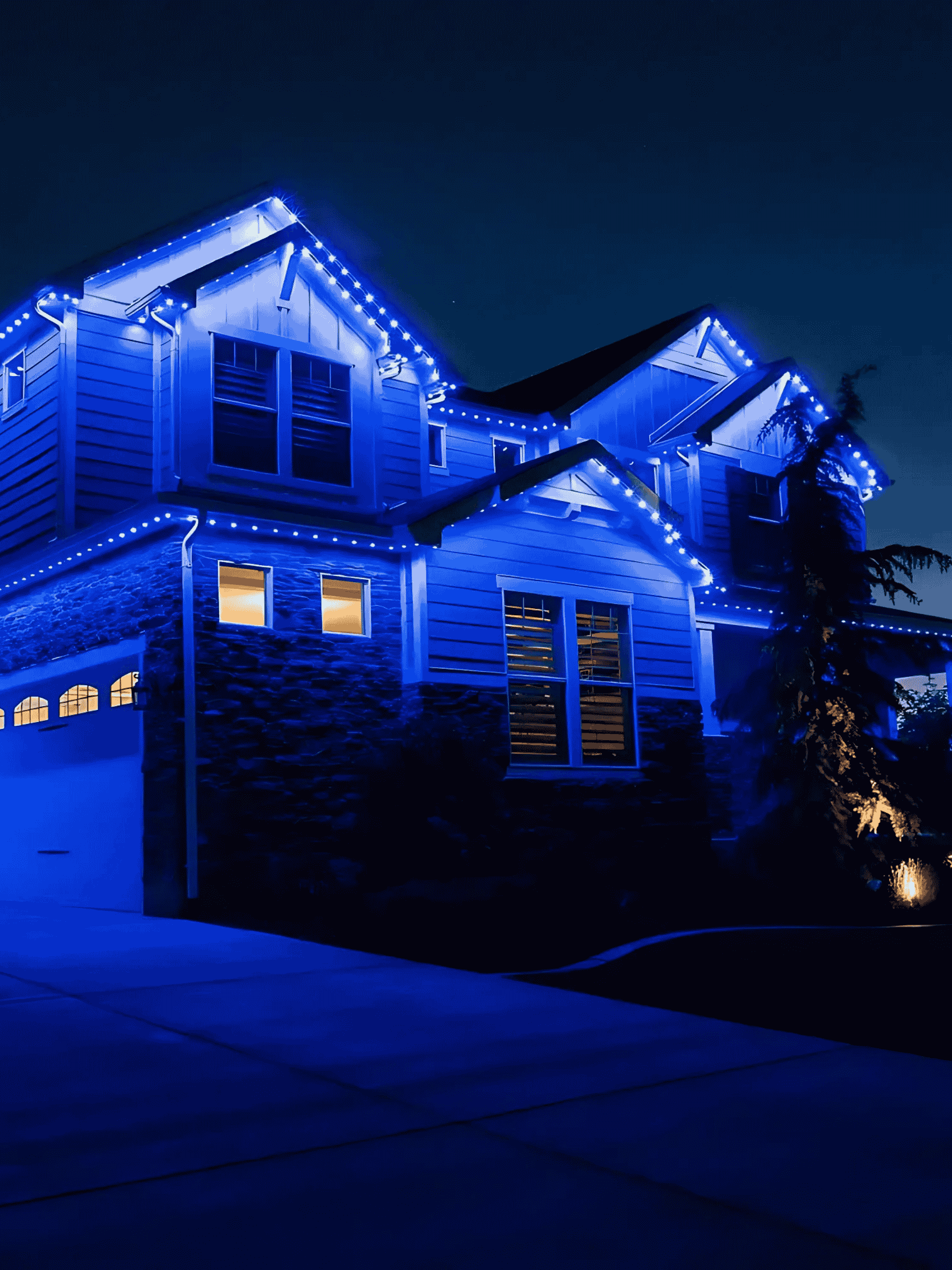 Blue‐tinted night view of a house illuminated by permanent LED exterior lights, representing Permanent Lights Calgary’s team.